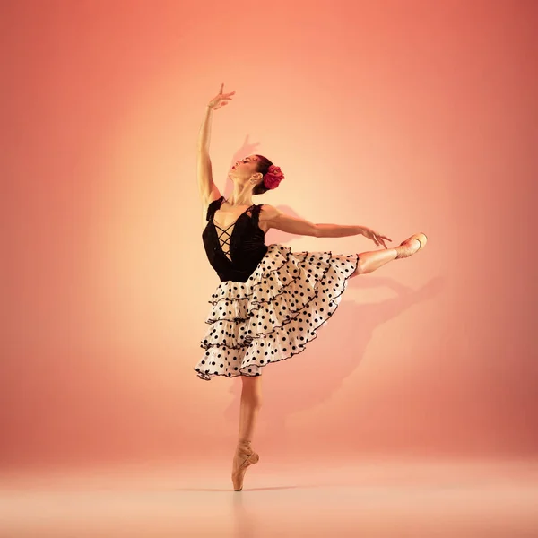 Jovem e incrivelmente bela bailarina está posando e dançando no estúdio vermelho cheio de luz. — Fotografia de Stock