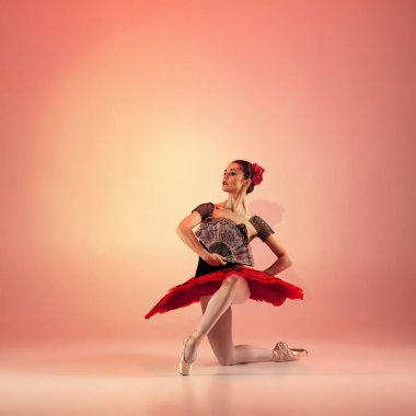 Genç ve inanılmaz güzel balerin ışık dolu kırmızı stüdyoda poz veriyor ve dans ediyor..