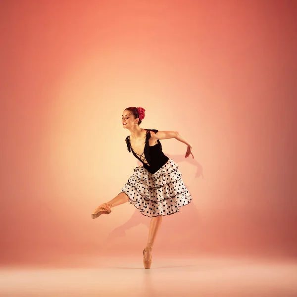 Jovem e incrivelmente bela bailarina está posando e dançando no estúdio vermelho cheio de luz. — Fotografia de Stock