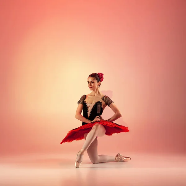 Jong en ongelooflijk mooi ballerina poseert en danst in rode studio vol licht. — Stockfoto