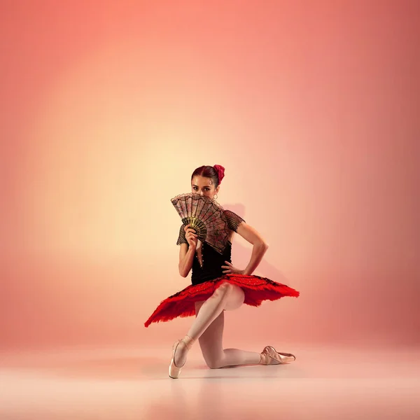 Jong en ongelooflijk mooi ballerina poseert en danst in rode studio vol licht. — Stockfoto