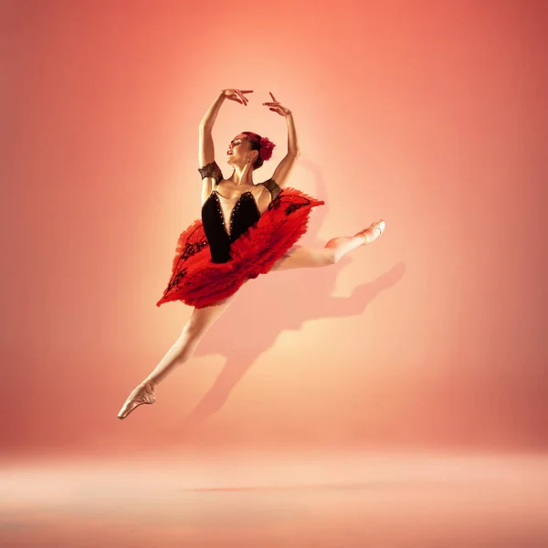 Mladá a neuvěřitelně krásná baletka pózuje a tančí v červeném studiu plném světla. — Stock fotografie