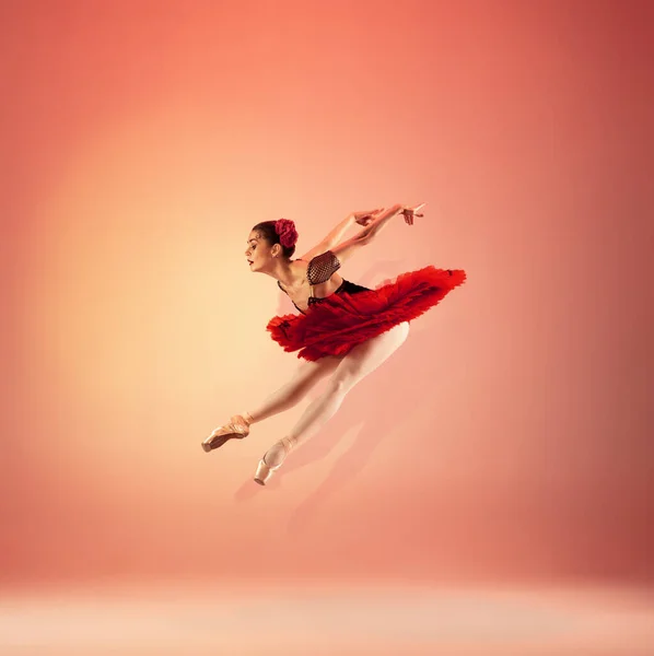 Joven e increíblemente hermosa bailarina posando y bailando en un estudio rojo lleno de luz. — Foto de Stock