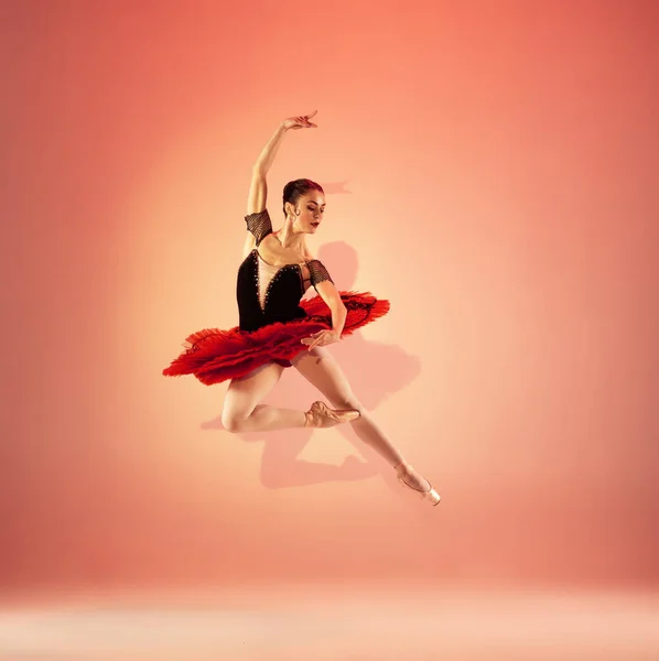 Jong en ongelooflijk mooi ballerina poseert en danst in rode studio vol licht. — Stockfoto