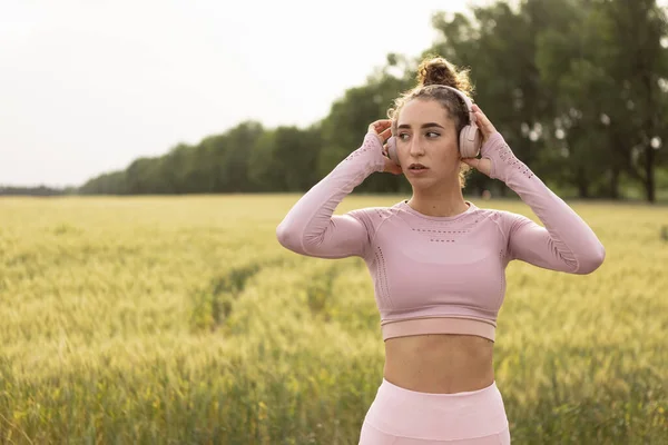 Jovem corredora, atleta está correndo na estrada em sol de verão. Bela mulher caucasiana a treinar, a ouvir música. Conceito de esporte, estilo de vida saudável, movimento, atividade. — Fotografia de Stock