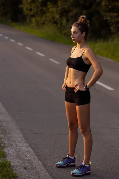 Jonge vrouwelijke loper, atleet is joggen op de weg in de zomer zon. Prachtige blanke vrouw training, luisteren naar muziek. Begrip sport, gezonde levensstijl, beweging, activiteit. — Stockfoto