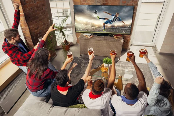 Gembira, bahagia sekelompok besar orang muda menonton pertandingan olahraga bersama di sofa di rumah. — Stok Foto