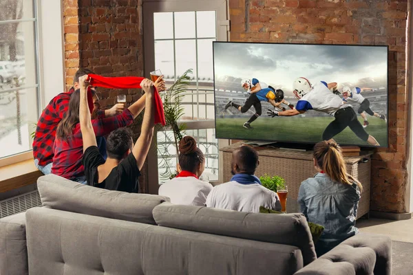余暇。興奮しました,自宅でソファの上で一緒にスポーツ試合を見ている若い人たちの幸せな大きなグループ. — ストック写真