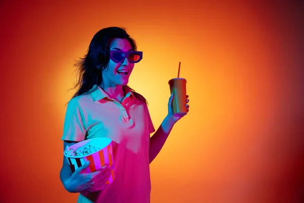 Eccitato in occhiali 3D e con popcorn. Ritratto femminile caucasico isolato su sfondo rosso studio in luce rosa al neon. Bellissimo modello maschile. — Foto Stock