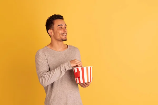Crazy shocked, flying popcorn. Caucasian young mans portrait isolated on blue studio background. Beautiful male model in casual style. — Stock Photo, Image