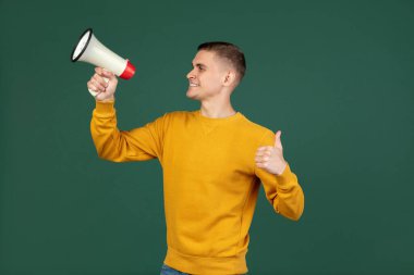 Genç beyaz adamın portresi yeşil stüdyo arka planında izole edilmiş bir şekilde poz veriyor ve reklam için kopyalama alanı var. İnsan duyguları kavramı