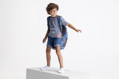 Beyaz stüdyo arka planında izole edilmiş büyük bir kutunun üzerinde duran beyaz anaokulu çocuğu. Kopyalama. Çocukluk, eğitim, duygu kavramı