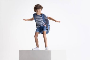 Beyaz stüdyo arka planında izole edilmiş büyük bir kutunun üzerinde duran beyaz anaokulu çocuğu. Kopyalama. Çocukluk, eğitim, duygu kavramı