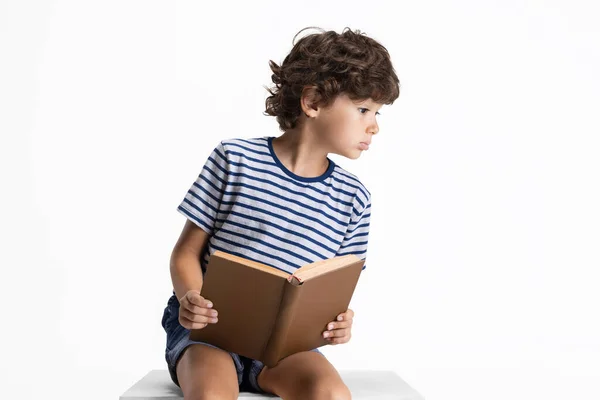 Retrato de niño preescolar caucásico sentado y leyendo libro aislado sobre fondo blanco del estudio. Copyspace. Infancia, educación, concepto de emociones — Foto de Stock