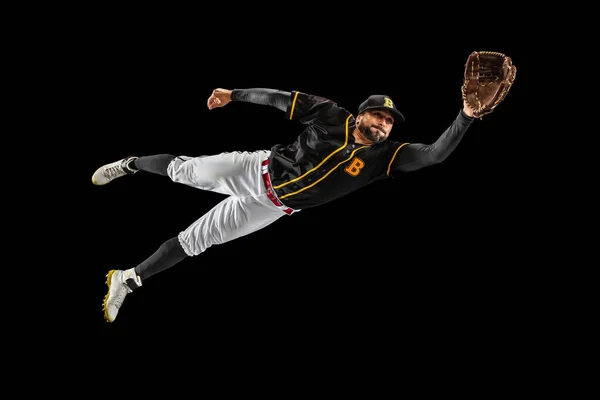 Vliegen. Honkbalspeler, catcher in sportuniform en apparatuur die geïsoleerd op een zwarte studio-achtergrond oefent. Team sport concept — Stockfoto