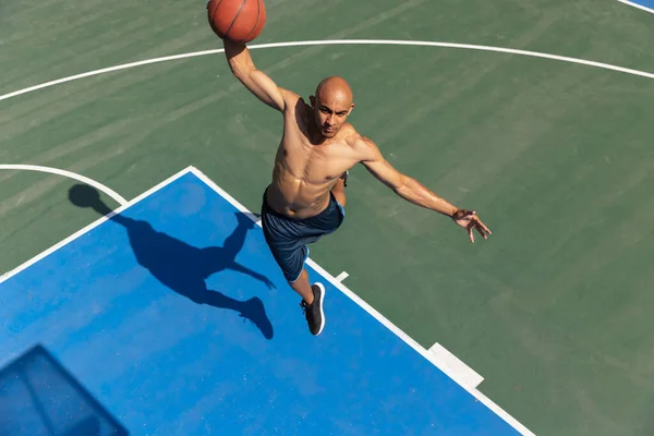 Fuerte musculoso afroamericano jugador de baloncesto masculino de entrenamiento en el estadio público de la calle, cancha deportiva o palyground al aire libre. Juegos de verano deporte. —  Fotos de Stock