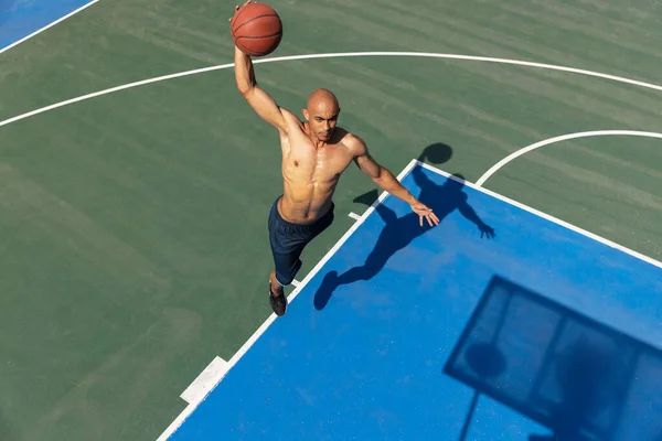 Hombre joven, jugador de baloncesto masculino africano musculoso que juega baloncesto en el estadio público de la calle, cancha deportiva o palyground al aire libre. Juegos de verano deporte. —  Fotos de Stock