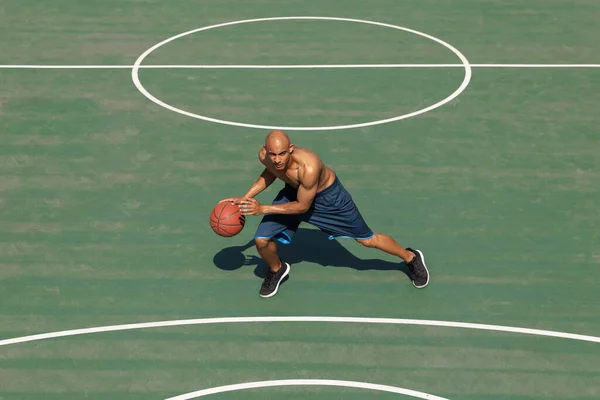 Un jugador de baloncesto afroamericano masculino entrenando en el estadio público callejero, cancha deportiva o palyground al aire libre. Concepto de estilo de vida activo saludable, movimiento, hobby. —  Fotos de Stock