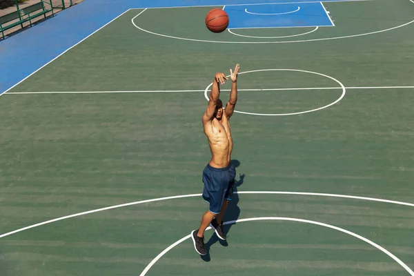 Fuerte musculoso afroamericano jugador de baloncesto masculino de entrenamiento en el estadio público de la calle, cancha deportiva o palyground al aire libre. Concepto de estilo de vida activo saludable, movimiento, hobby. —  Fotos de Stock