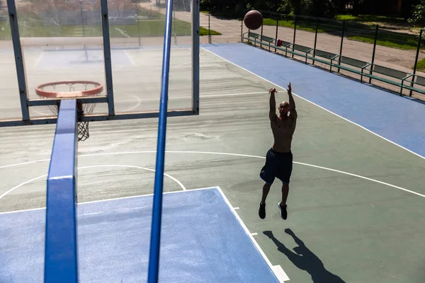 Вид сверху молодого человека, баскетболиста-мужчины, играющего в баскетбол на уличном общественном стадионе, спортивной площадке или палитраже на открытом воздухе. Летние игры. — стоковое фото