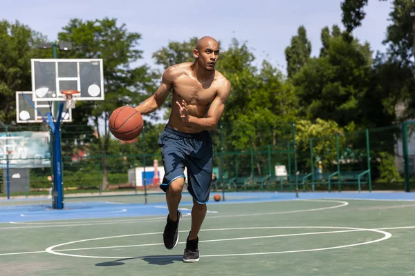 Stark muskulös afrikansk-amerikansk manliga basketspelare utbildning på gatan offentliga stadion, idrottsplan eller palyground utomhus. Sommar sport spel. — Stockfoto
