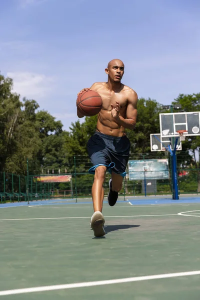 Jugador de baloncesto masculino afroamericano joven entrenando en el estadio público callejero, cancha deportiva o palyground al aire libre. Juegos de verano deporte. —  Fotos de Stock