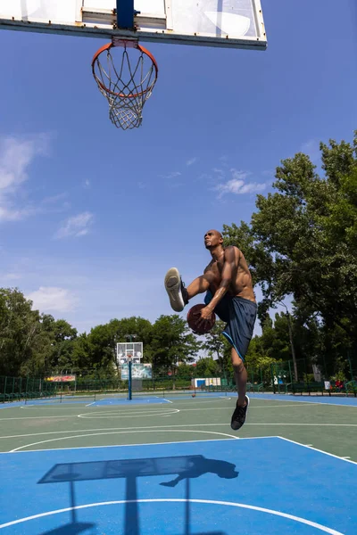 Hombre joven, jugador de baloncesto masculino africano musculoso que juega baloncesto en el estadio público de la calle, cancha deportiva o palyground al aire libre. Juegos de verano deporte. —  Fotos de Stock