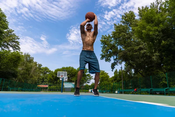 Fuerte musculoso afroamericano jugador de baloncesto masculino de entrenamiento en el estadio público de la calle, cancha deportiva o palyground al aire libre. Concepto de estilo de vida activo saludable, movimiento, hobby. —  Fotos de Stock