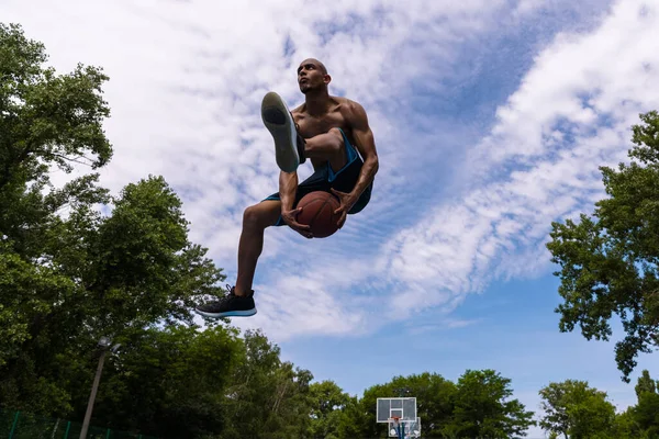 Jovem, jogador de basquete masculino africano muscular que joga basquete no estádio público de rua, quadra esportiva ou palyground ao ar livre. Jogos de esporte de verão. — Fotografia de Stock