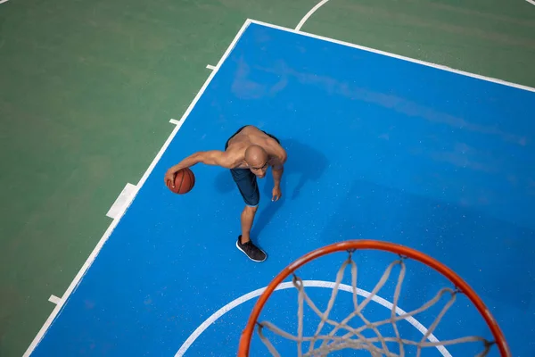 Vista ad alto angolo di giovane uomo, giocatore di basket maschile che gioca a basket allo stadio pubblico di strada, campo sportivo o palyground all'aperto. Giochi sportivi estivi. — Foto Stock