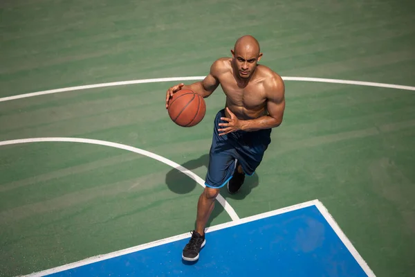 Fuerte musculoso afroamericano jugador de baloncesto masculino de entrenamiento en el estadio público de la calle, cancha deportiva o palyground al aire libre. Concepto de estilo de vida activo saludable, movimiento, hobby. —  Fotos de Stock