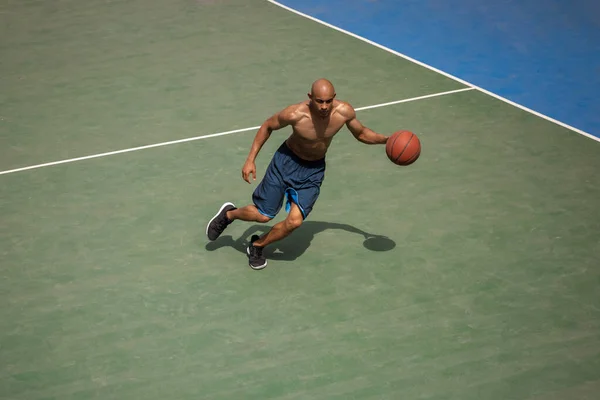 Fuerte musculoso afroamericano jugador de baloncesto masculino de entrenamiento en el estadio público de la calle, cancha deportiva o palyground al aire libre. Juegos de verano deporte. —  Fotos de Stock