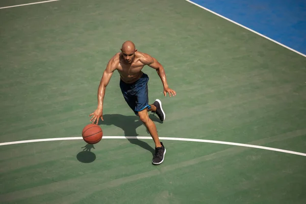 Draufsicht auf einen jungen Mann, einen männlichen Basketballspieler, der im öffentlichen Straßenstadion, Sportplatz oder Palyground im Freien Basketball spielt. Sommersportspiele. — Stockfoto