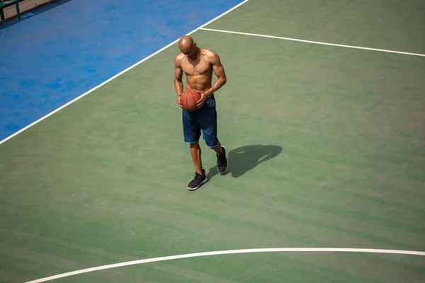 Un giocatore di basket maschile afro-americano che gioca allo stadio pubblico di strada, al campo sportivo o al palyground all'aperto. Concetto di sano stile di vita attivo, movimento, hobby. — Foto Stock