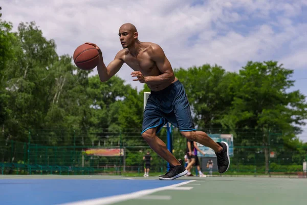 Forte allenamento muscolare giocatore di basket maschile afro-americano allo stadio pubblico di strada, al campo sportivo o al palyground all'aperto. Giochi sportivi estivi. — Foto Stock