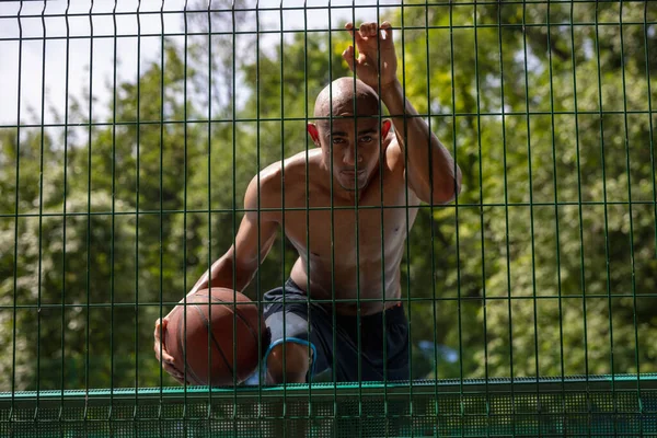 Joven hombre fuerte, jugador de baloncesto masculino en el estadio público de la calle, pista de deporte o palyground al aire libre. Concepto de estilo de vida activo saludable, movimiento, hobby. —  Fotos de Stock