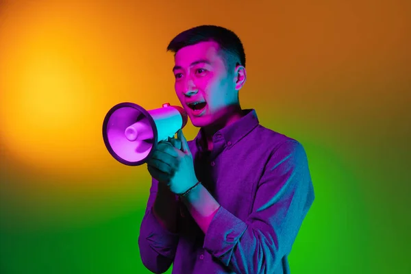 Retrato do jovem asiático isolado no fundo do estúdio em luz de néon verde gradiente, filtro de cor. Conceito de emoções humanas, expressão facial. — Fotografia de Stock