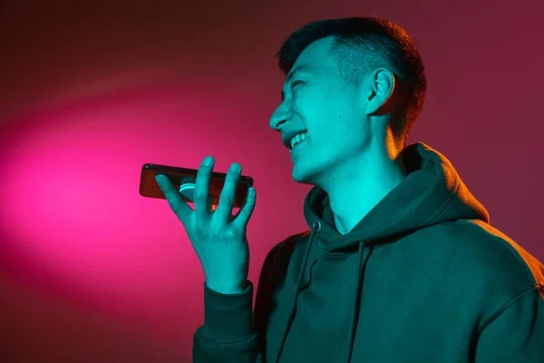 Gros plan portrait d'un jeune homme asiatique isolé en studio dans une lumière rouge fluo dégradée, filtre couleur. Concept d'émotions humaines, expression faciale. — Photo