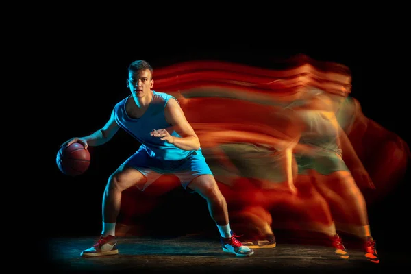 Giocatore professionista di basket maschile in uniforme blu che gioca a basket isolato su sfondo scuro studio in luce mista. Concetto di stile di vita sano, sport professionale, hobby. — Foto Stock