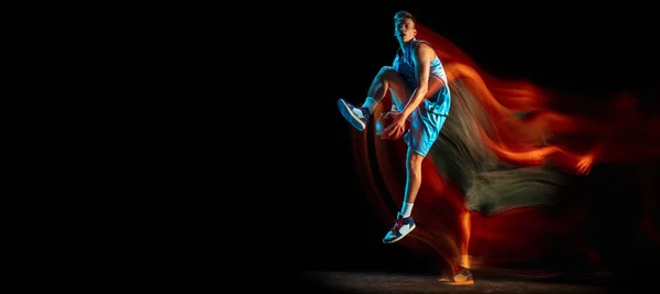 Młody biały mężczyzna koszykarz gra w koszykówkę odizolowany nad ciemnym tle studio w mieszanym świetle. Pojęcie zdrowego stylu życia, sportu zawodowego, hobby. — Zdjęcie stockowe