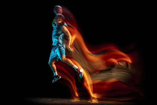 年轻的高加索人，男性篮球运动员在黑暗的工作室背景下，在混光中打篮球。健康生活方式、职业运动、业余爱好的概念. — 图库照片
