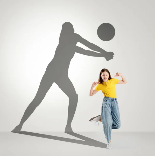 Conceptual image with preschool girl and shadow of female volleyball player on light gray background. Childhood and dream about big and famous future. — Zdjęcie stockowe