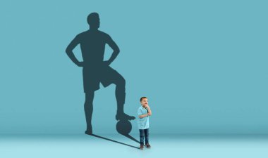 Çocukluk ve büyük ve ünlü bir gelecek hayal etmek. Çocuklu kavramsal imaj ve mavi arka planda formda bir erkek futbol oyuncusunun gölgesi. Hayaller, hayal gücü, eğitim kavramı.