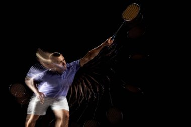 Genç bir erkek badminton oyuncusu, mekik eğitimi karanlık arka planda. Stroboskop etkisi.