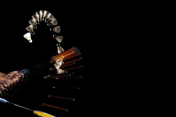 Close-up male hands with badminton racket and shuttlecock isolated over dak studio background with stroboscope effect. — Stock Fotó