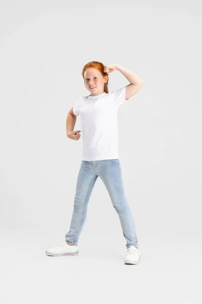 Belle petite fille rousse mignonne en tenue décontractée s'amusant isolé sur fond de studio blanc. Joyeux concept d'enfance. Enfant ensoleillé — Photo