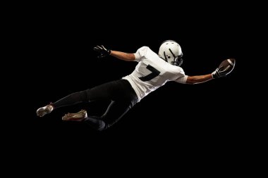 Portre genç Amerikan futbolcusu, siyah beyaz spor üniformalı sporcu karanlık stüdyo arka planında izole edilmiş. Profesyonel spor kavramı, şampiyonluk, rekabet.