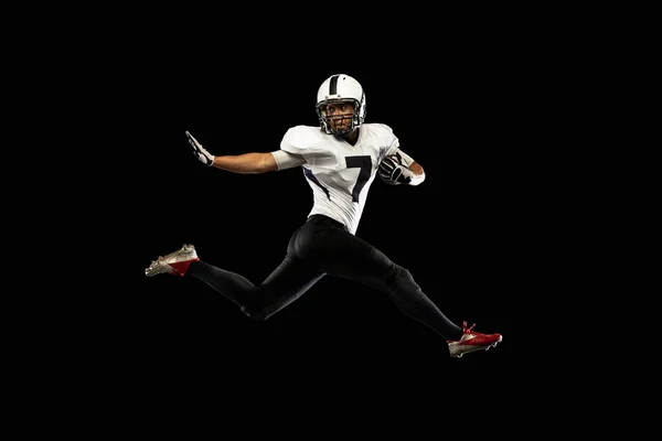 Retrato jovem jogador de futebol americano, atleta em preto branco treinamento uniforme de esportes isolado em fundo estúdio escuro. Conceito de esporte profissional, campeonato, competição. — Fotografia de Stock