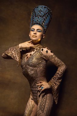 Nefertiti 'nin sanat performansındaki görüntüsü gibi genç bir kadın. Kahverengi renkli arka planda izole edilmiş. Retro biçimi, dönemin karşılaştırması.