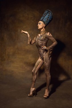 Nefertiti 'nin sanat performansındaki görüntüsü gibi genç bir kadın. Kahverengi renkli arka planda izole edilmiş. Retro biçimi, dönemin karşılaştırması.